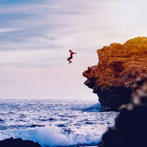 Ein Mann springt von Klippen ins offene Meer.