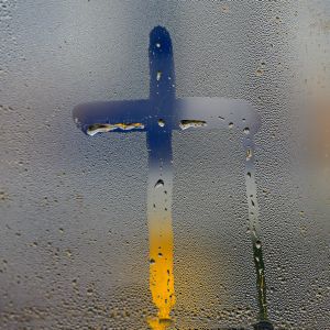 Kreuz auf beschlagener Fensterscheibe