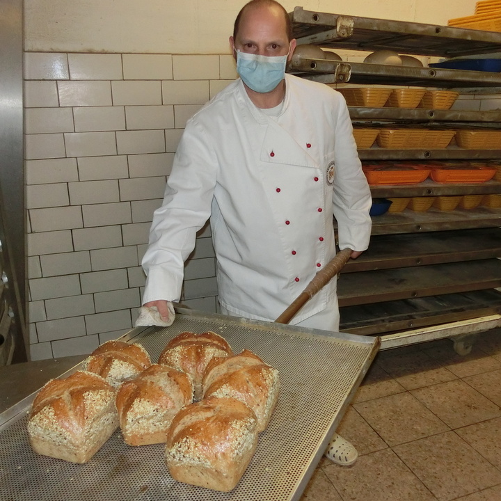Auf dem Blech hat Alexander Koch, der eine starke Sehschwäche hat, frisch gebackenes Brot – die Heilwasserbrotsorte mit einer Krone.